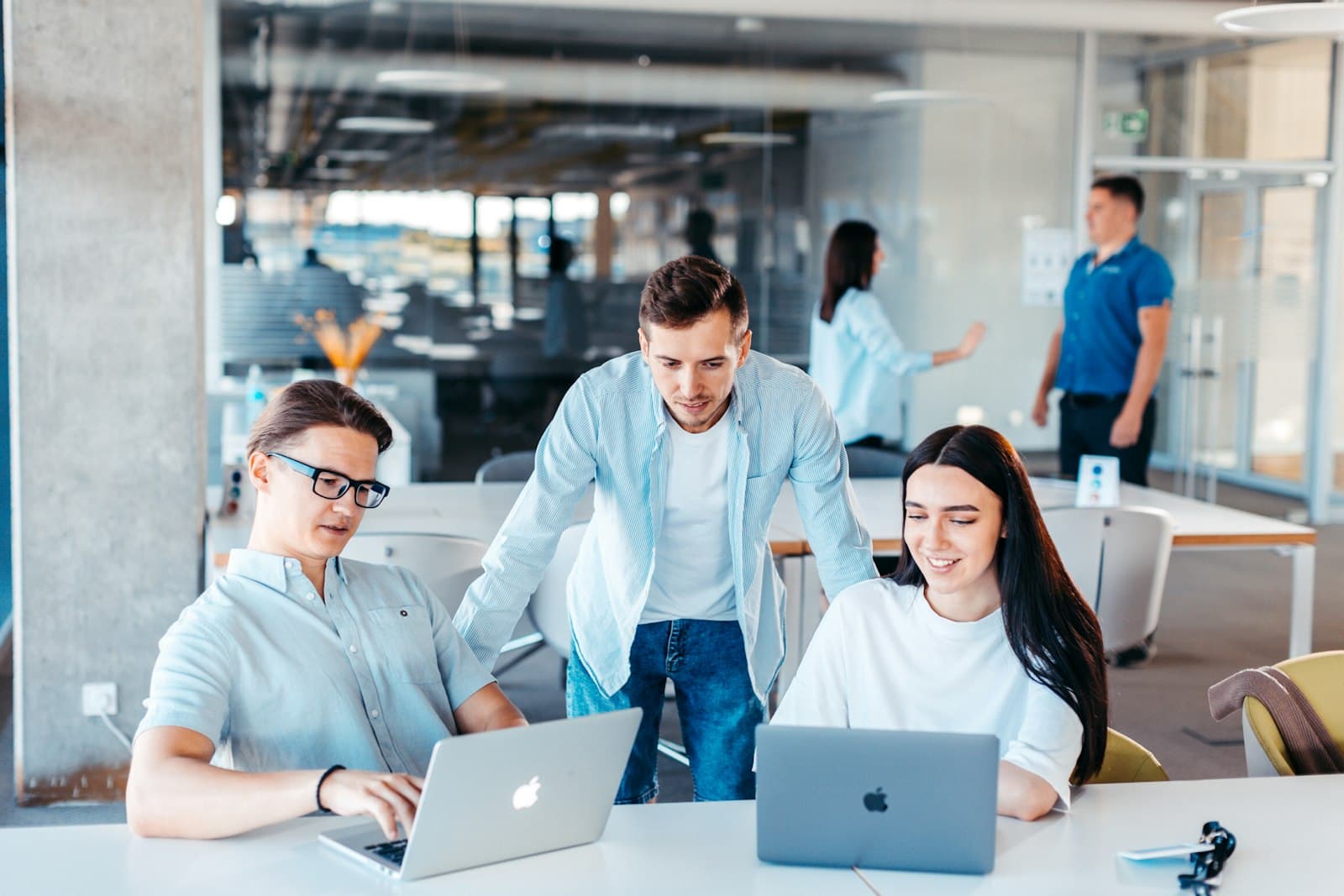 Three colleagues working together at laptops in a bright open-plan office
